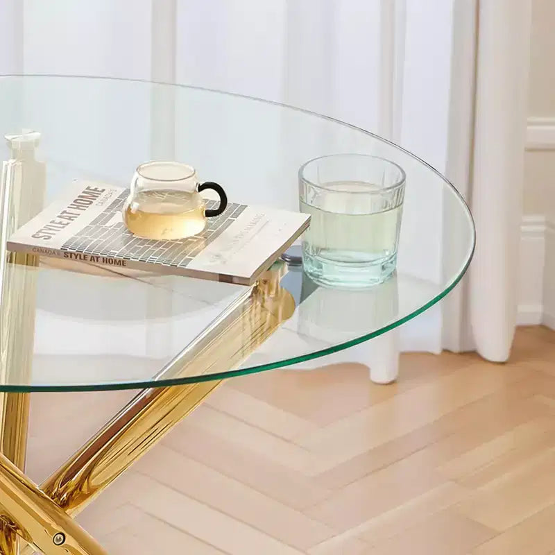 Elegante tavolo da pranzo dorato con ripiano in vetro e gambe incrociate